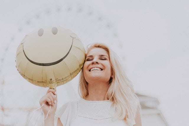 pretty woman at a festival with a smily face baloon